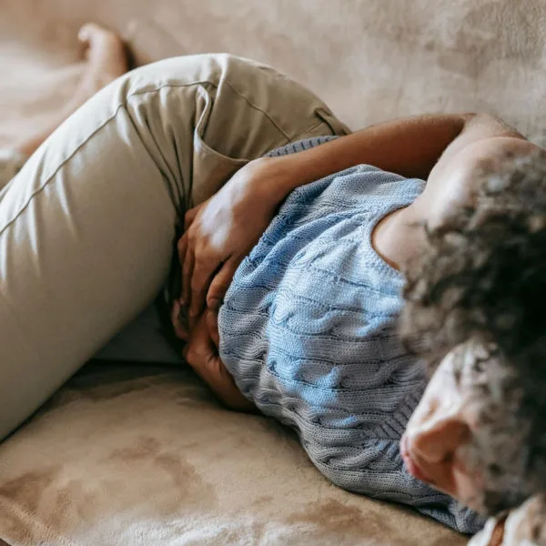 Woman lying on couch with pelvic discomfort from prolapse